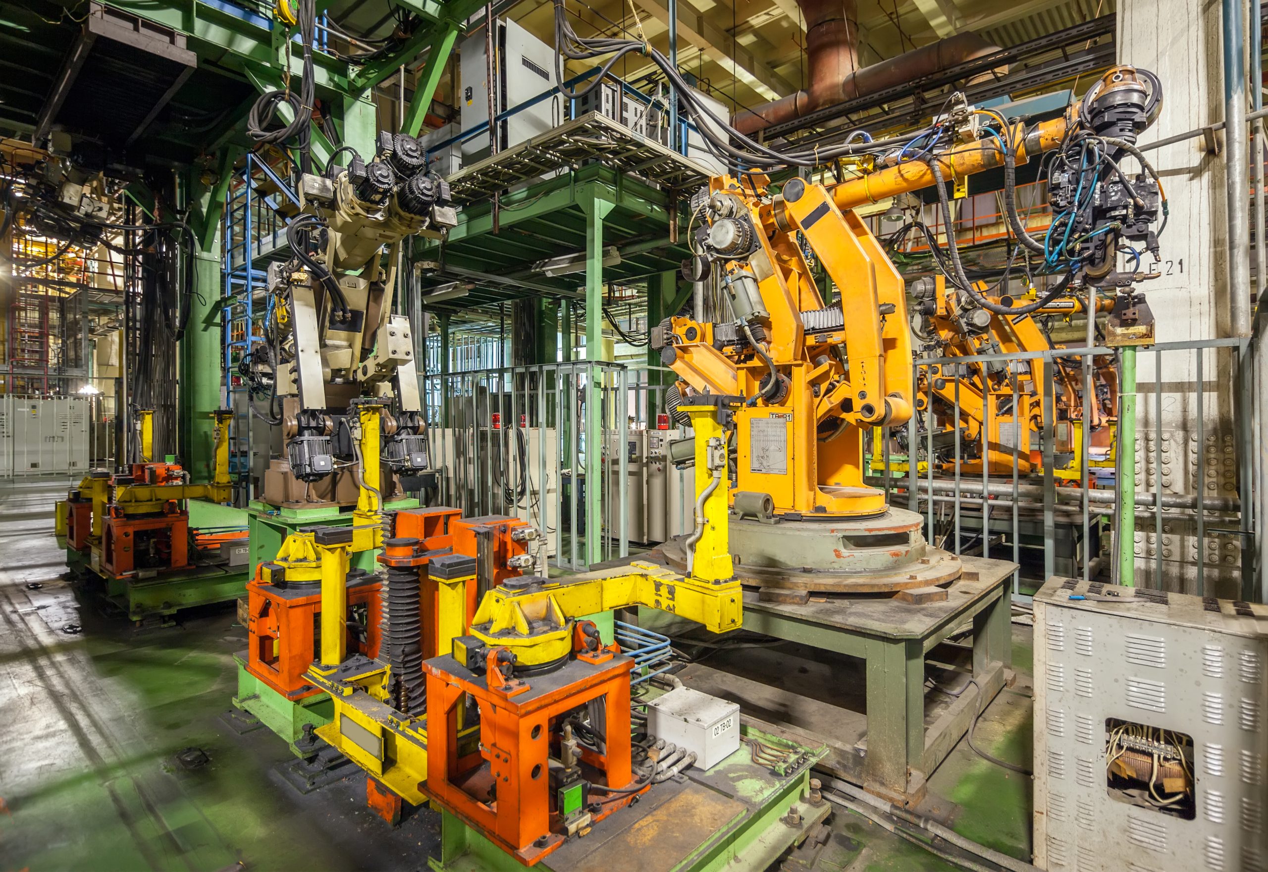 Bankrupt and abandoned automobile plant. Yellow robots welding cars in a production line